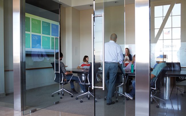 Une réunion de 5 personnes dans une salle devant un Surface Hub.